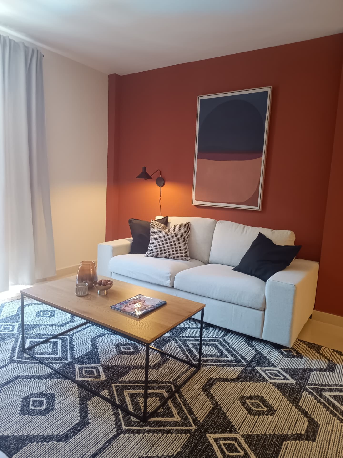 Wohnzimmer mit weißem Sofa, Terrakottawand, abstraktem Kunstdruck und ethnischem Teppich