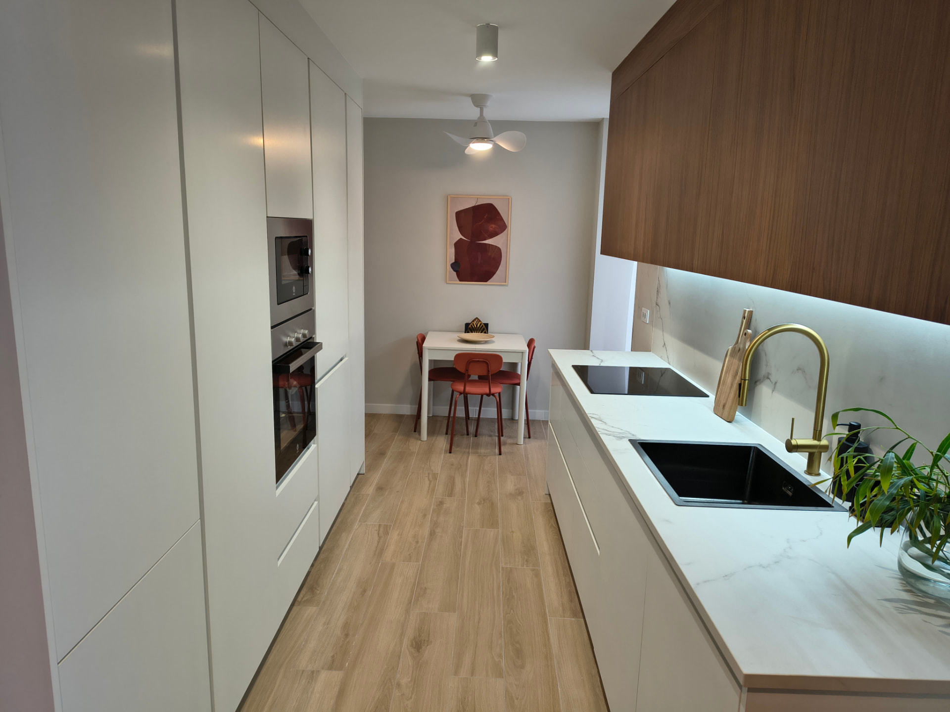 Weiße Küche mit Holzfronten und roten Stühlen