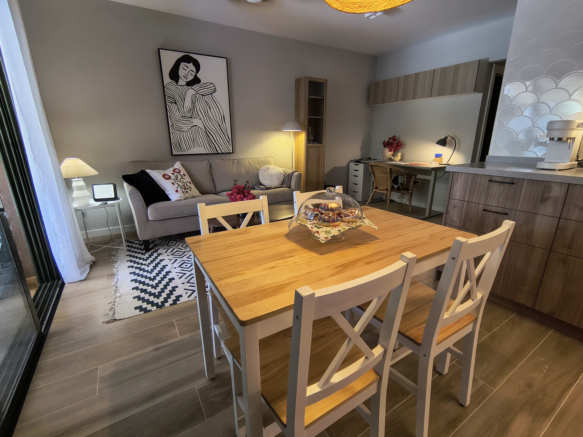 Wohn-Esszimmer mit Holztisch, grauem Sofa und geometrischem Teppich
