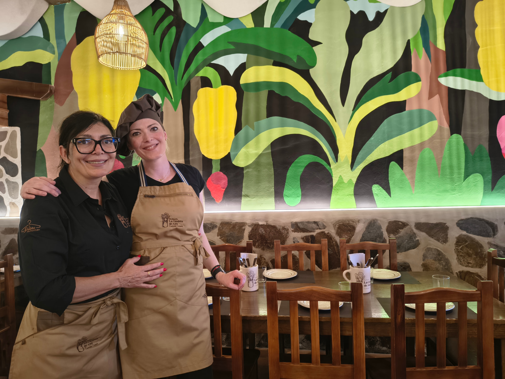 Restaurantinterieur mit großem tropischem Wandbild und Holzmöbeln